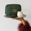 Hand holding a green cosmetic bag with Bescher products on a white background